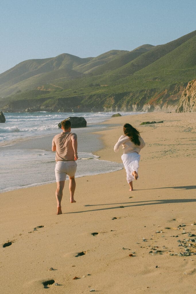 Engaged couple walking barefoot during sunset in Big Sur