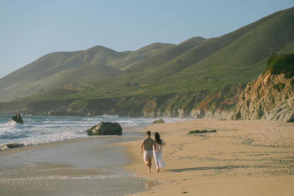 Engaged couple walking barefoot during sunset in Big Sur